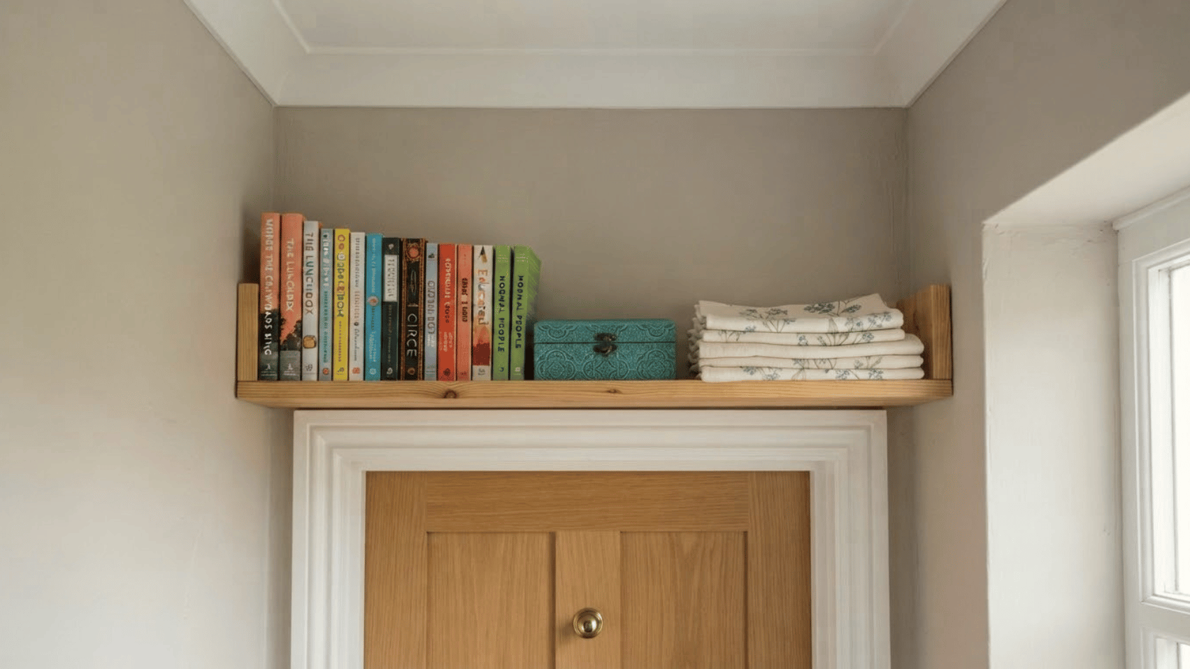 An above door wall shelving uses unused vertical space for books, linens, and boxes while keeping the bedroom floor clear.