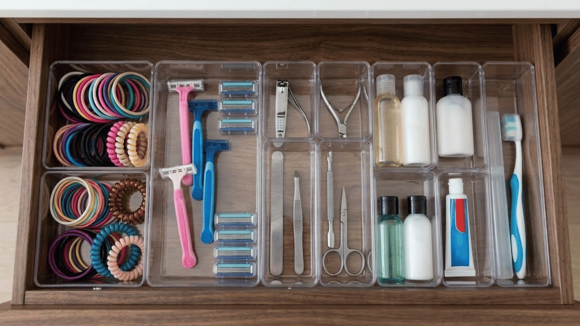 drawer organizers holding hair ties, razors, nail tools, and travel-size products in a bathroom drawer